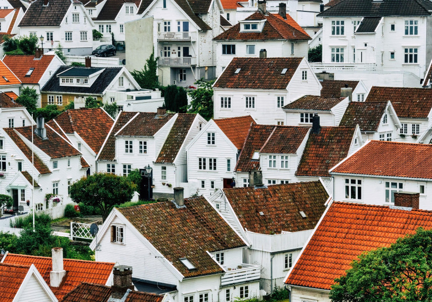 Ein Foto von dicht aneinanderstehenden, weißen Häusern mit roten Ziegeldächern, die sich einen Hang hinaufziehen.
