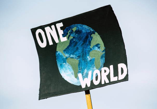 Demonstrationsplakat mit einer Erdkugel und dem Schriftzug ONE WORLD