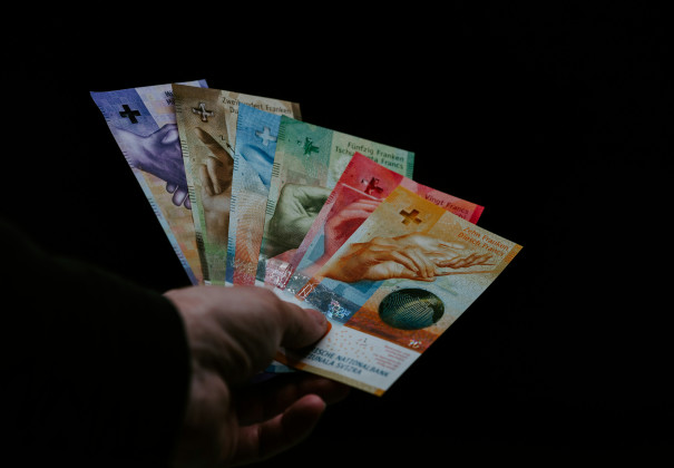 Eine Hand, die alle sechs verschiedenen Schweizer Banknoten gefächert in einer Hand hält