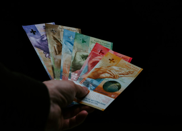 Eine Hand, die alle sechs verschiedenen Schweizer Banknoten gefächert in einer Hand hält